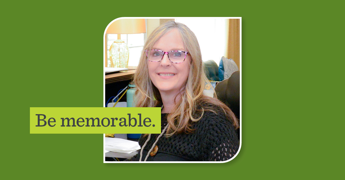 photograph of woman smiling at her desk in a black top with a name tag on. Overlay text on image reads 