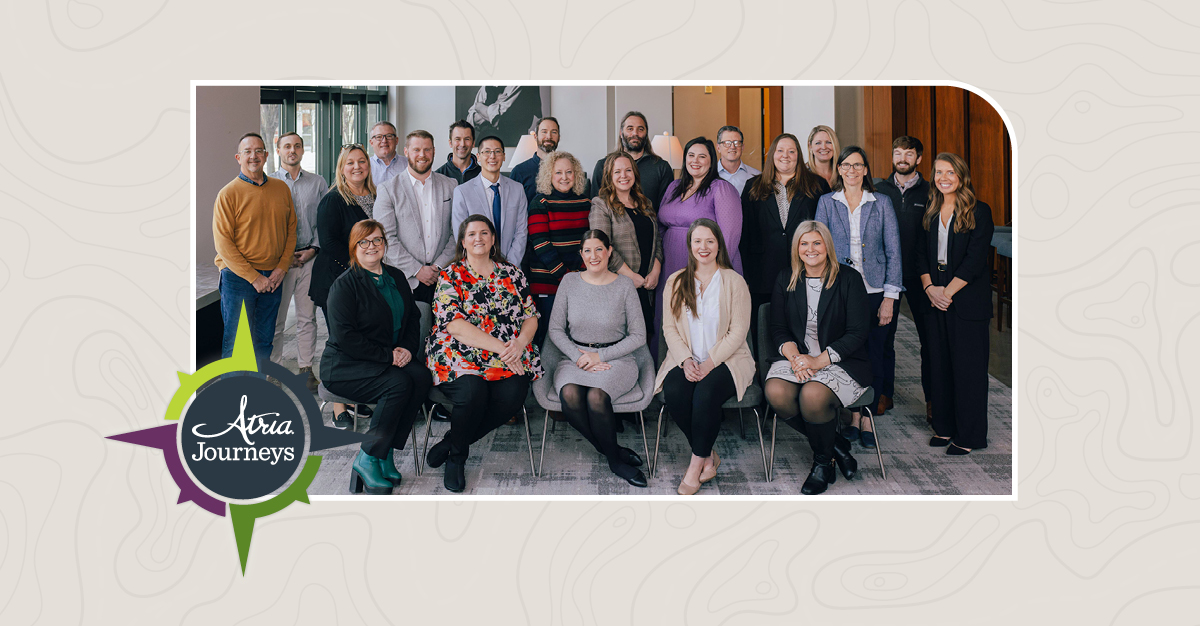 Group of professionally dressed people smiling, with an overlay that says Atria Journeys.