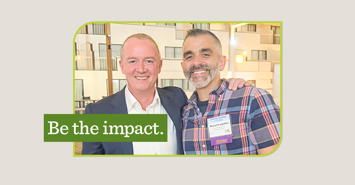 Two men smiling with one arm around the other. A green overlay says 